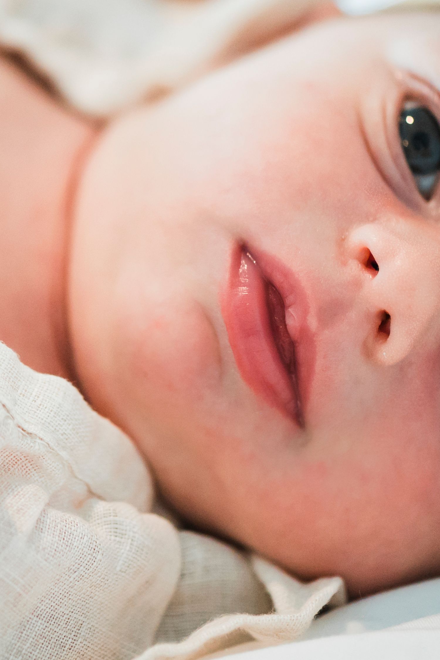 Close-up portrait showing soft facial features against white fabric creating a dreamy ethereal mood.