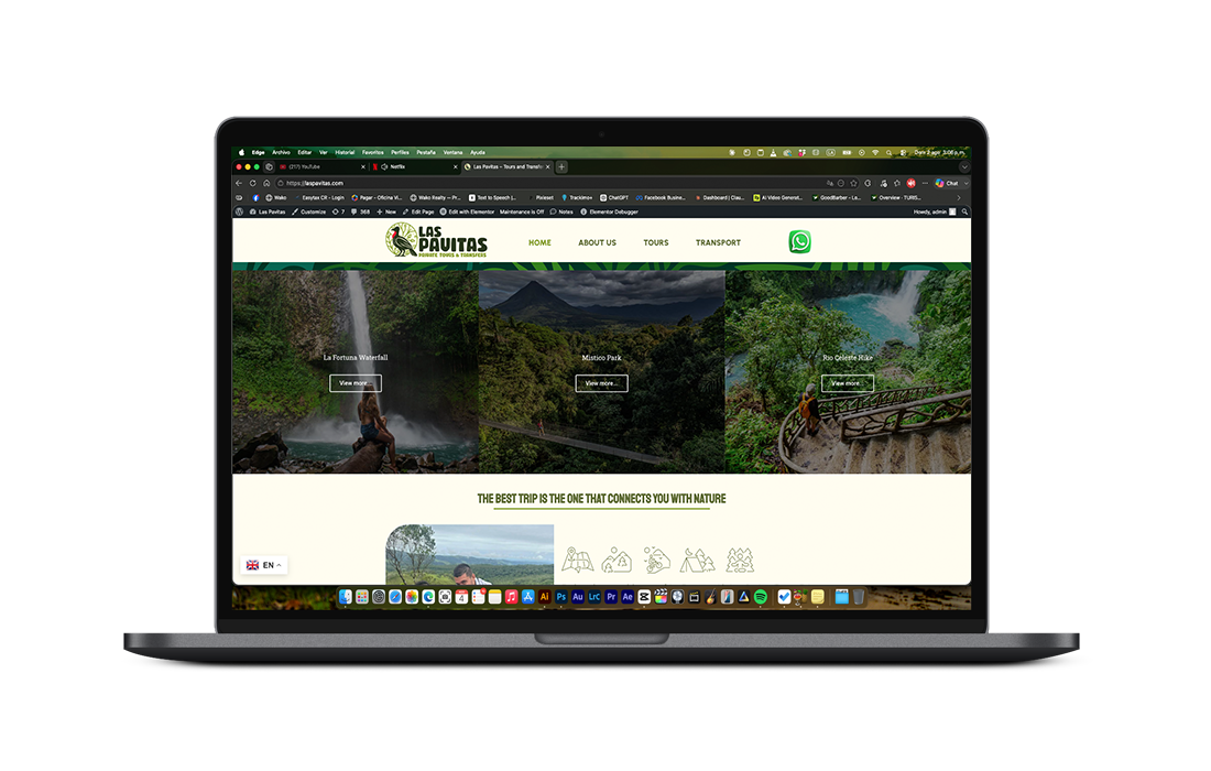 Laptop displaying a nature travel website with lush green forest and waterfall imagery promoting eco-tourism.