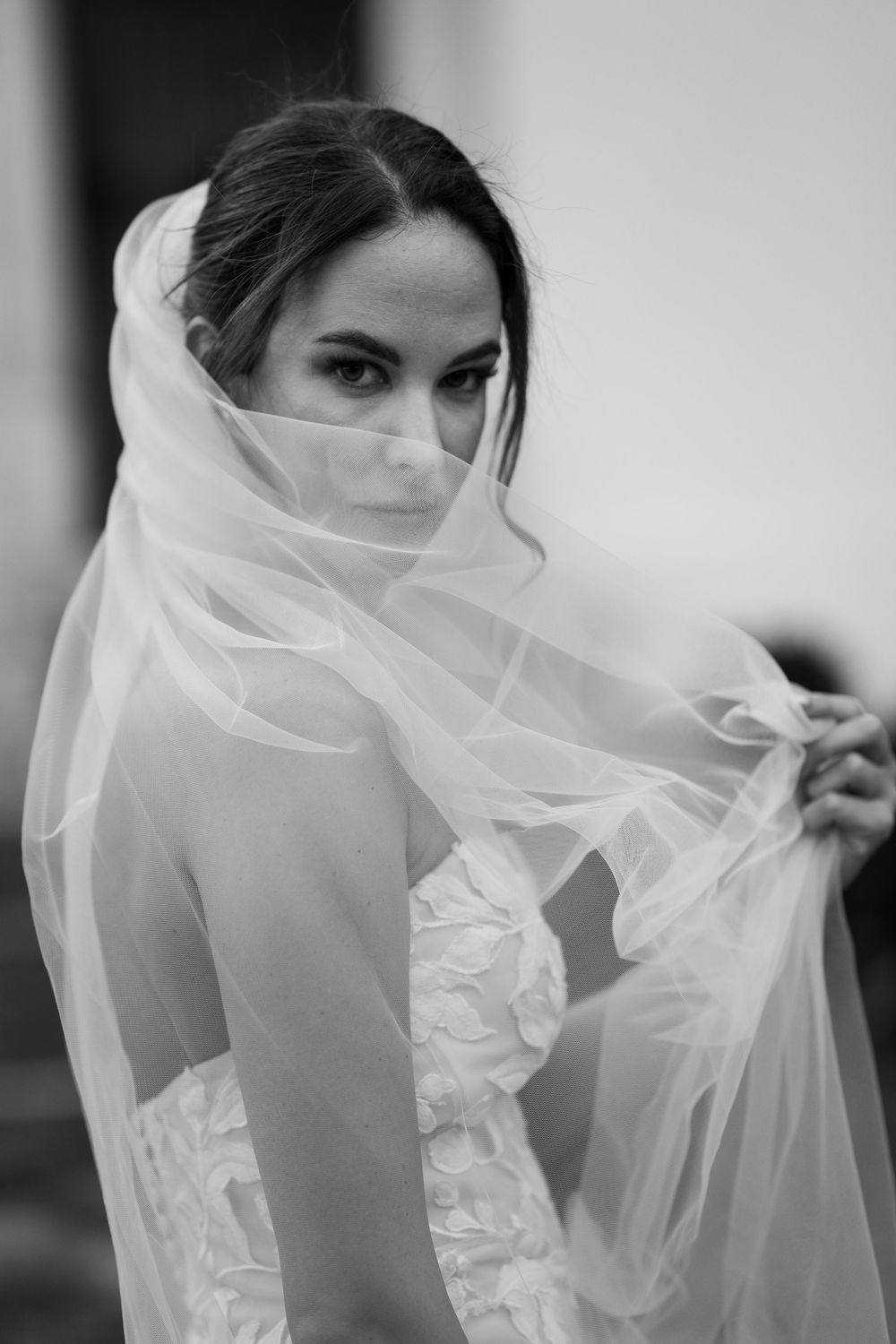 A black and white photograph showing a bride wearing a flowing white veil captured in an artistic sequence.