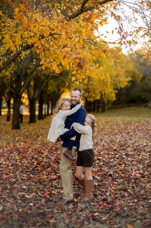 A scenic autumn photoshoot in a park with fallen leaves and vibrant yellow foliage on the trees above.