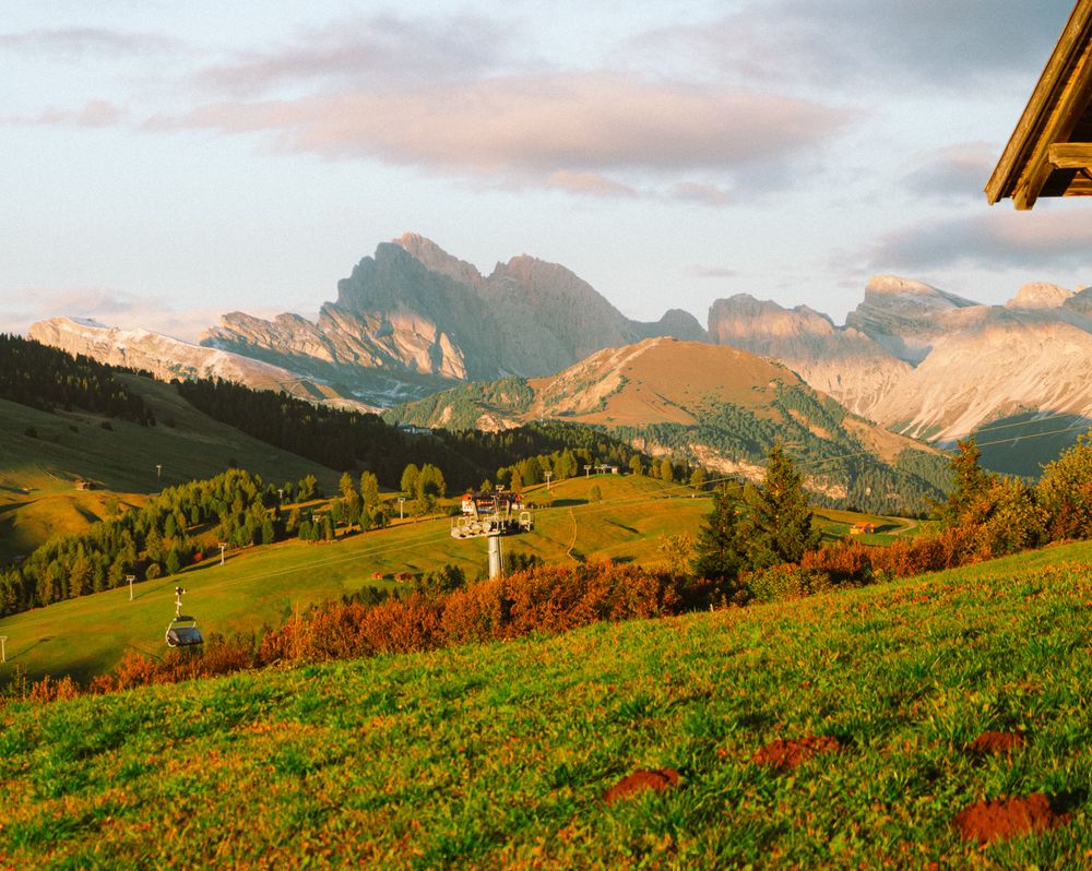 Rolling alpine hills with scattered houses under soft clouds