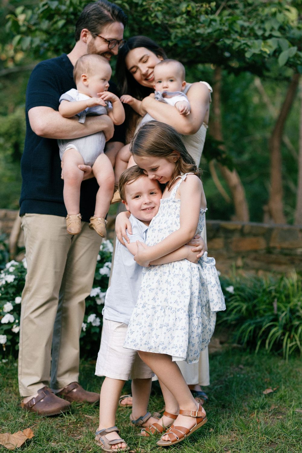 A sweet family moment captured outdoors with everyone embracing and showing affection.