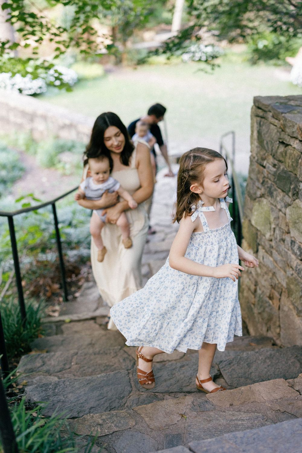 A charming outdoor family scene on stone steps with greenery in the background.