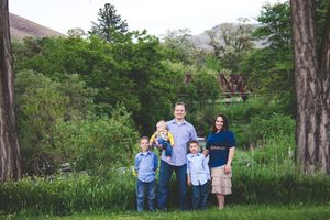 Extended family gathered outdoors for group photo in natural wooded setting.