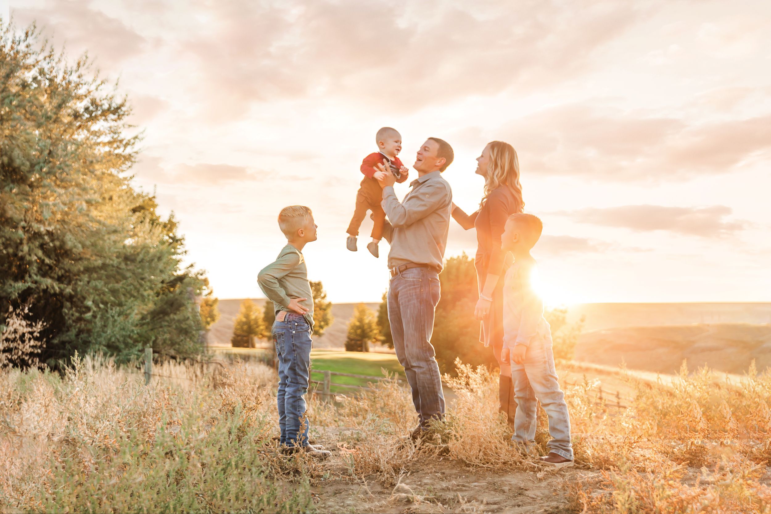 Family enjoying a golden sunset together in a scenic outdoor field.