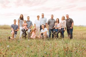 Large family group portrait in flowering meadow during golden hour.