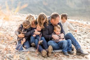 Family members sitting close together on rocky terrain during sunset.