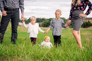 Family members standing and playing in tall grass field.