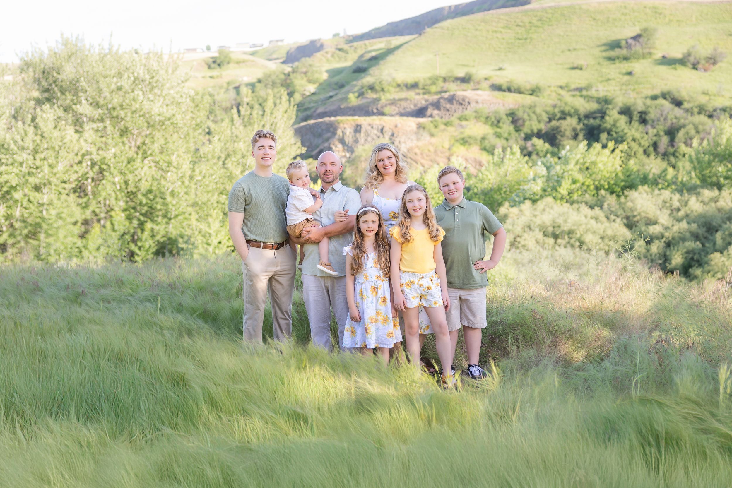 Extended family gathering on hillside during golden hour photography session.