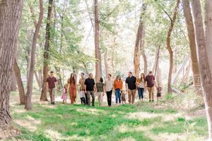 A group photo session taking place in a wooded area with tall trees and natural lighting.