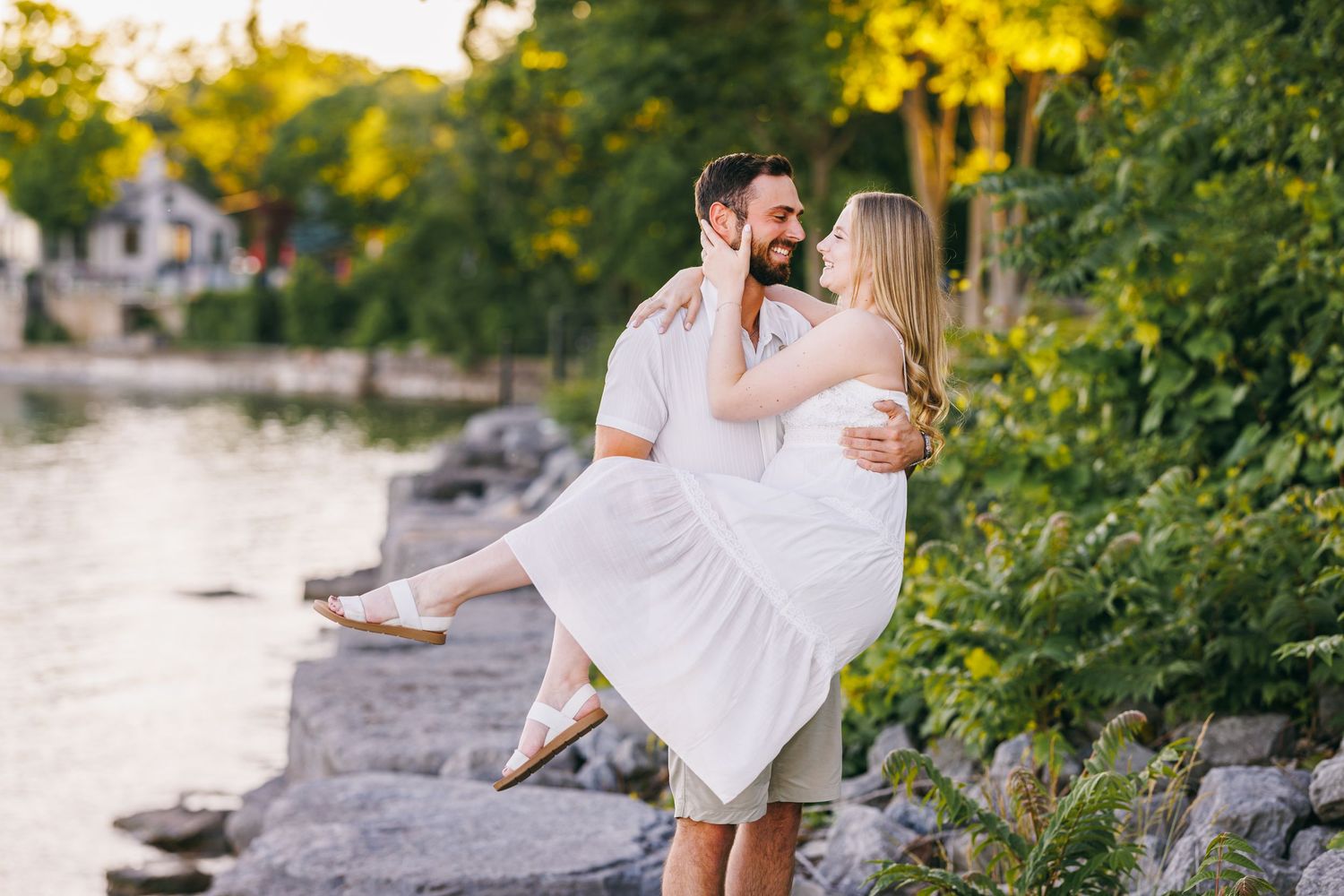 People enjoying a romantic sunset beach engagement photoshoot in white outfits with soft golden light filtering through trees.