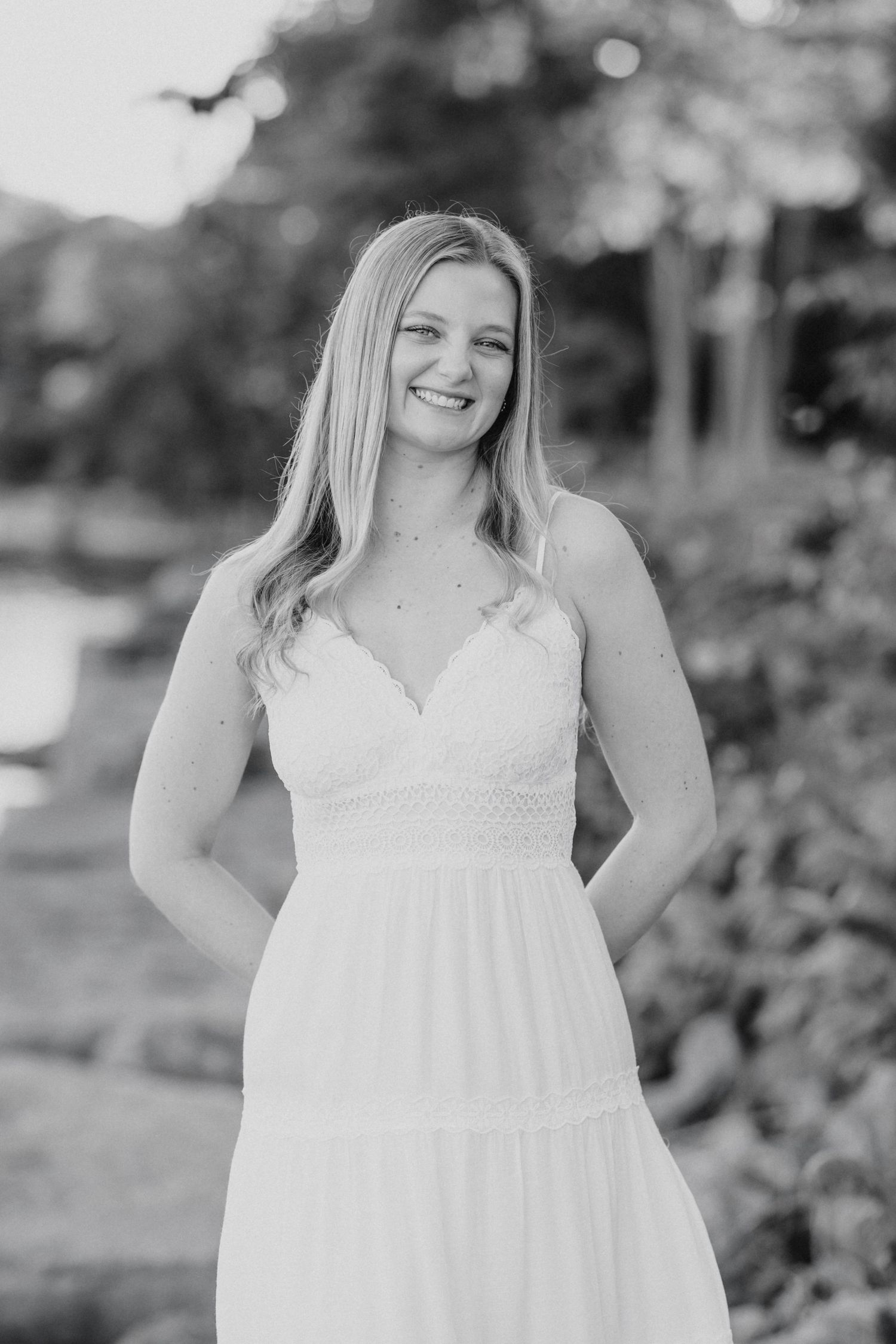 Three black and white portraits show a woman in a white summer dress posing outdoors with joyful expressions.