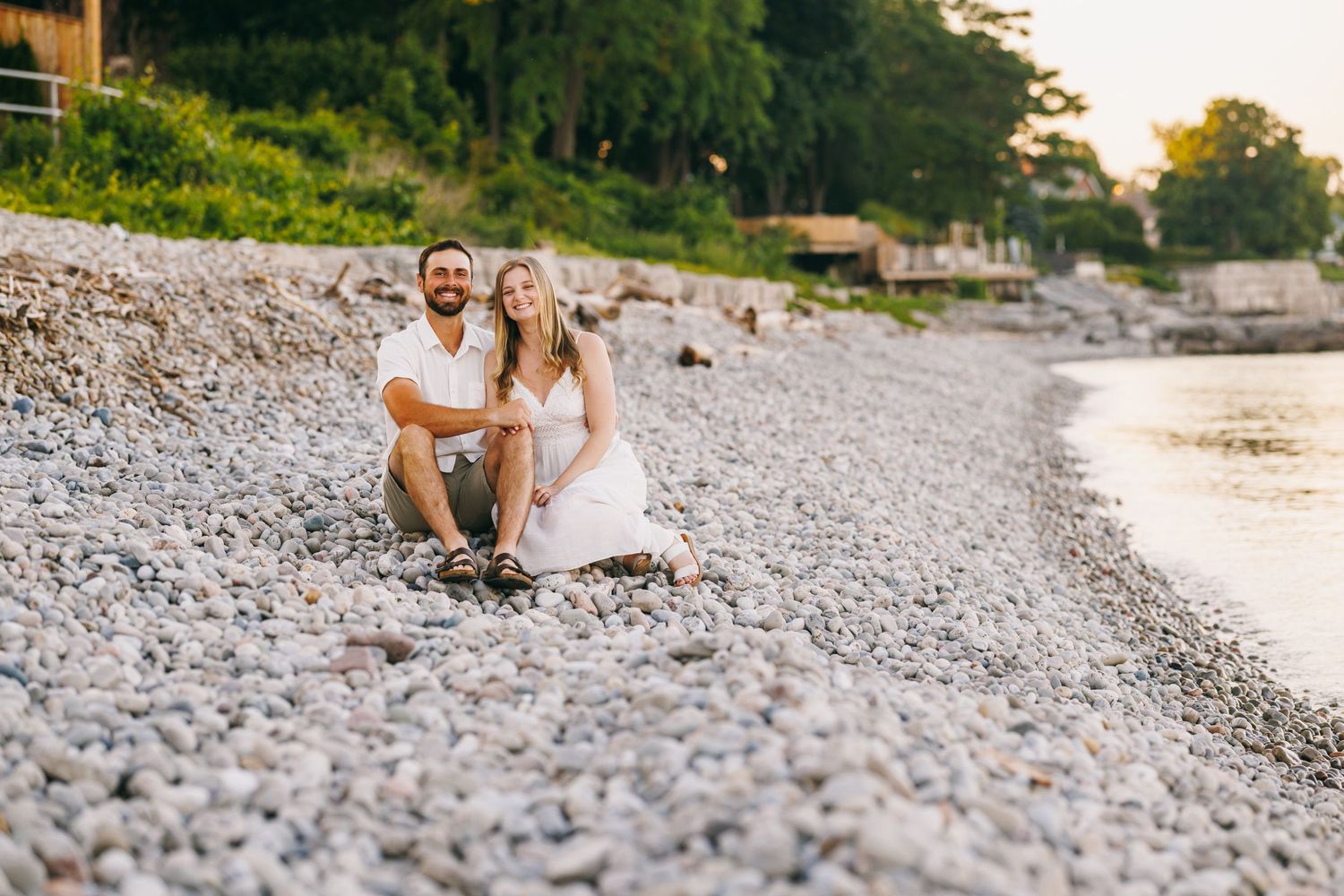 Romantic couple sitting together on a rocky beach at sunset.