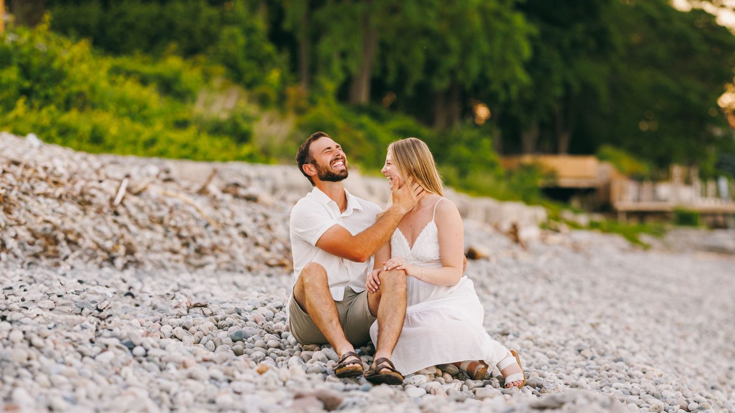 Two people relax on a rocky beach near Lake Michigan with calm water in the background.