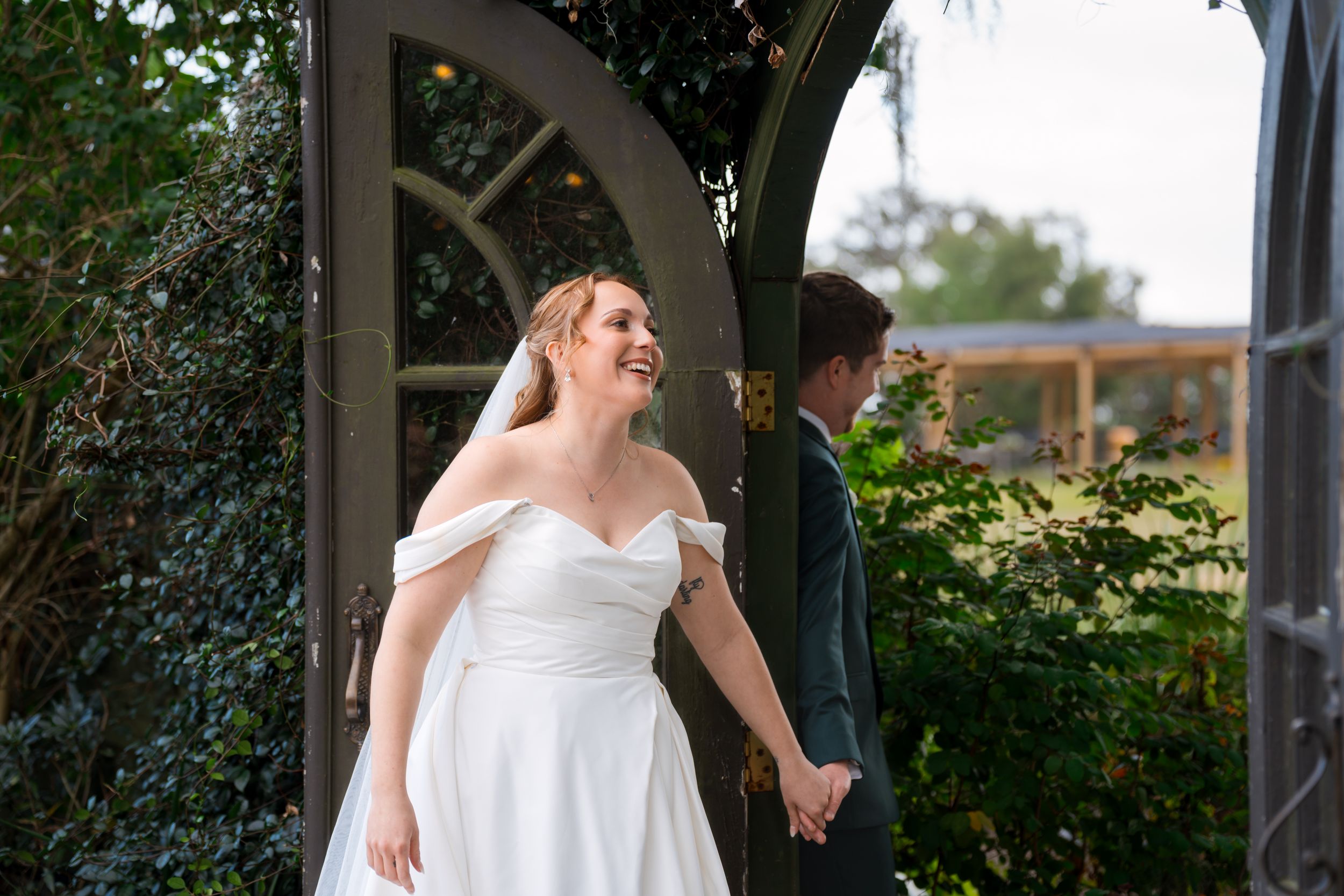 A couple shares a romantic first look moment before their wedding ceremony under an arched garden doorway.