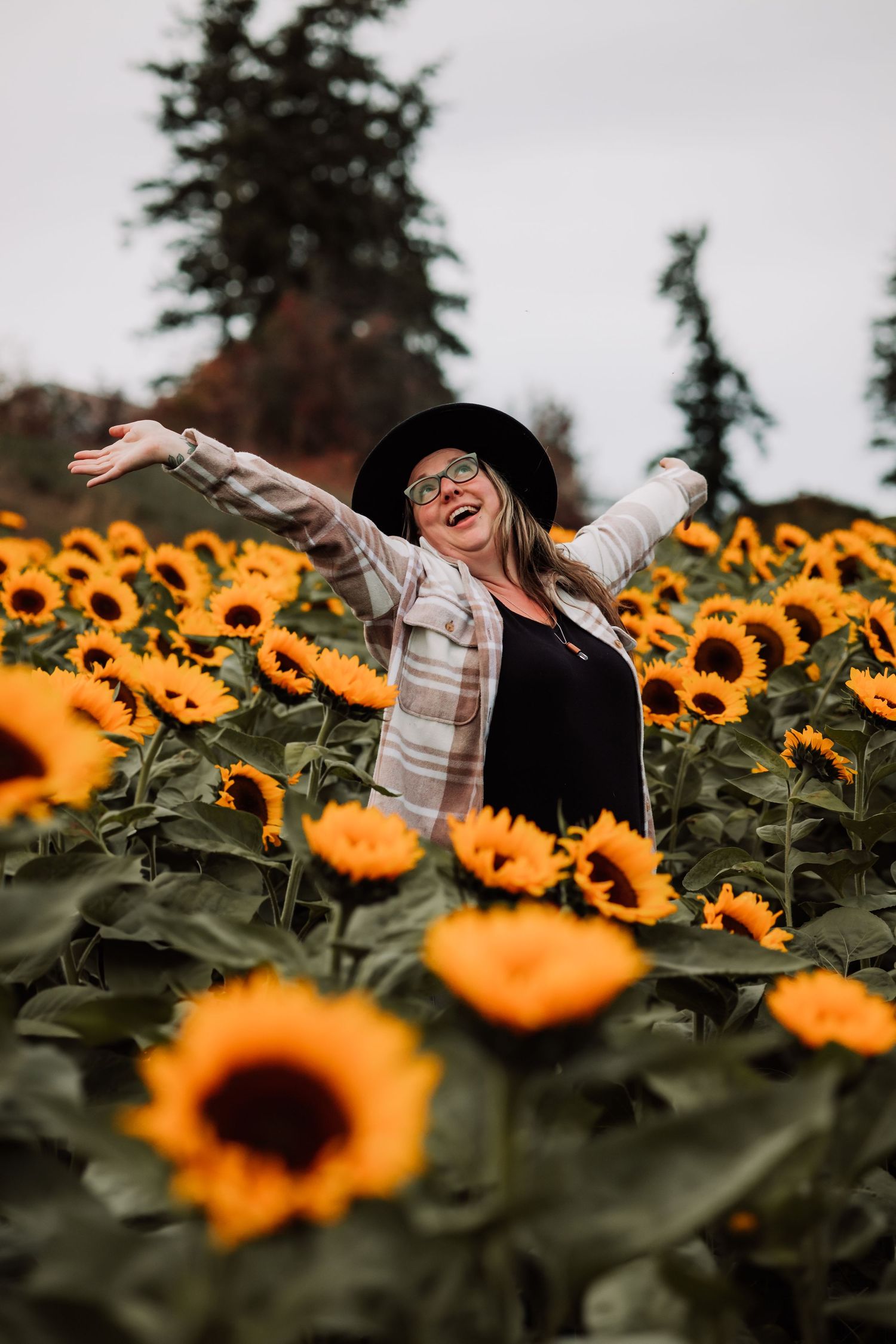 Woman dances joyfully in a field of sunflowers at the Bloom Sunflower Festival in Armstrong BC