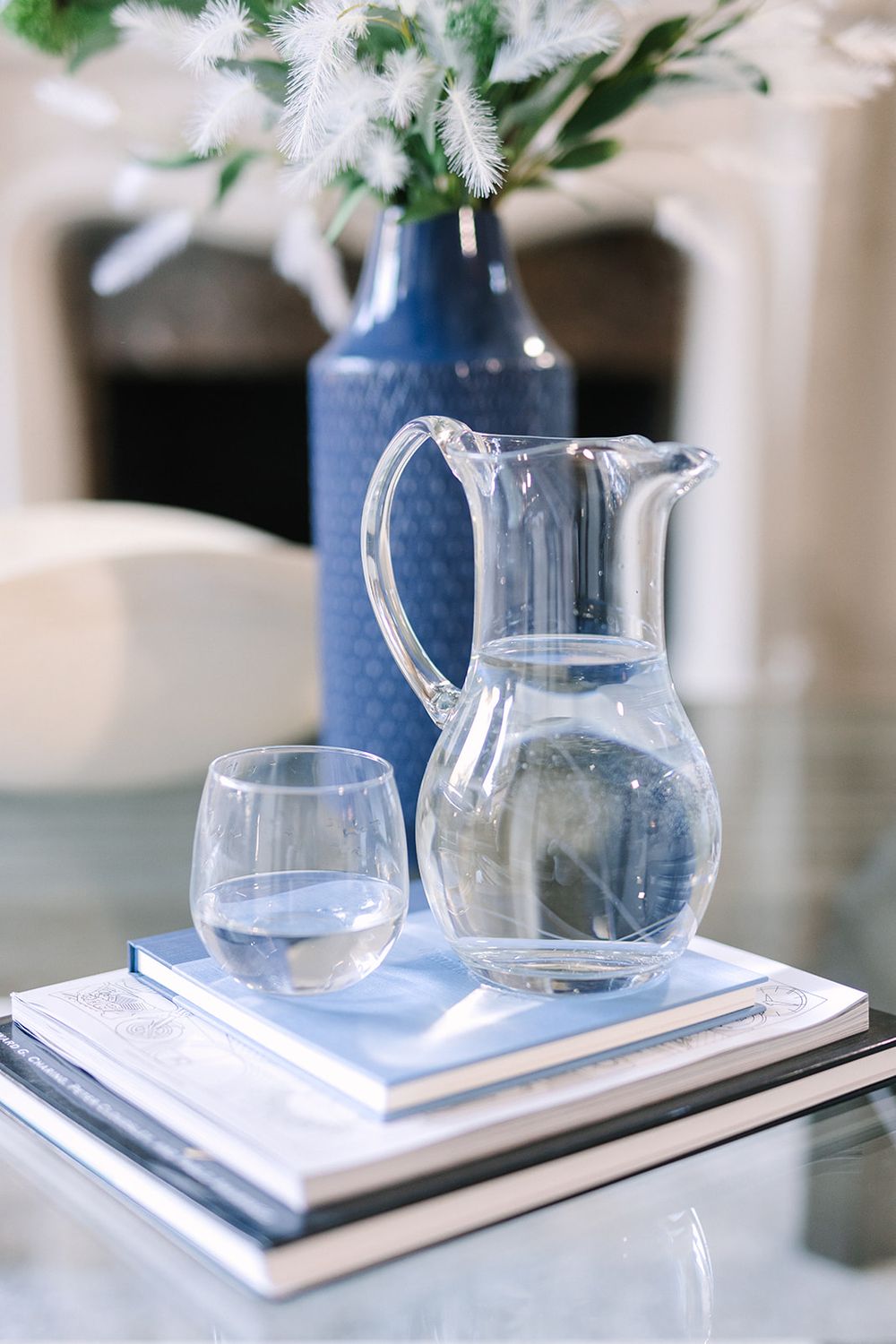 Sequence of four glass water pitchers on white serving trays arranged in a stylish minimalist display.