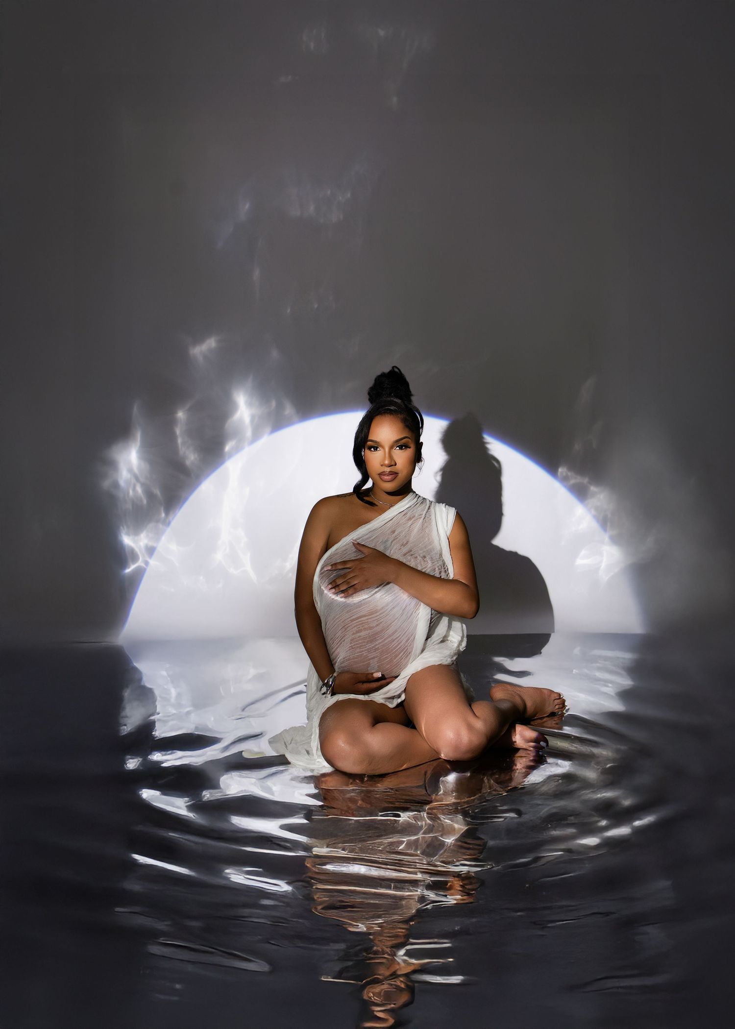 Artistic photo of a person wearing white fabric sitting in reflective water with a glowing moon backdrop.