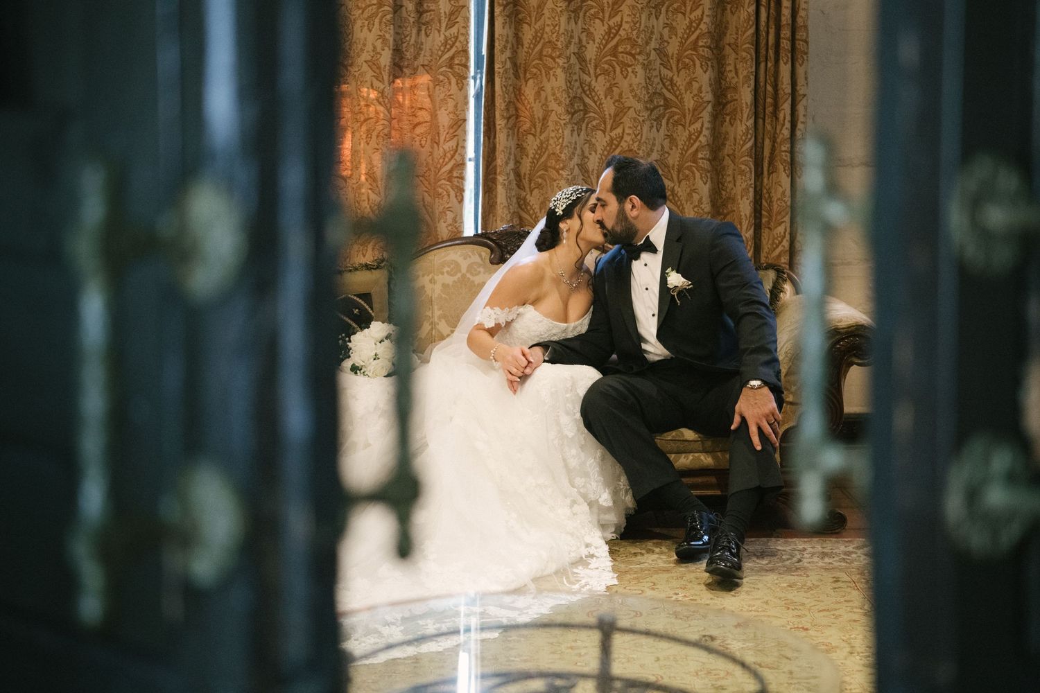 Intimate wedding moment photographed through window panes with vintage styling.