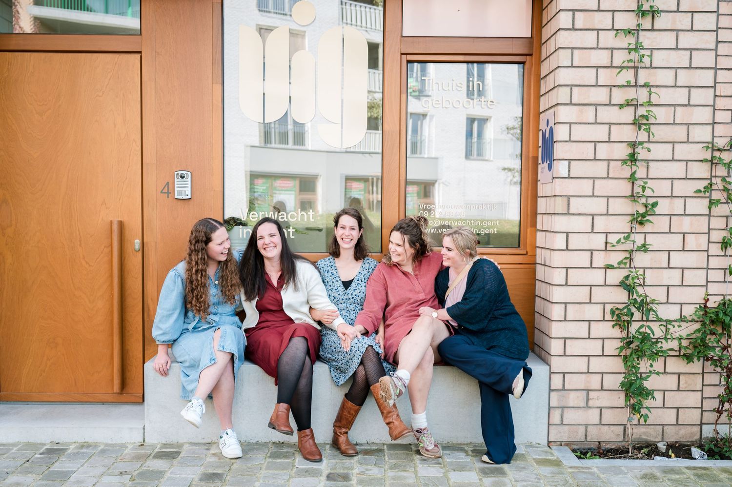 Friends sitting together on a concrete step outside a brick building.