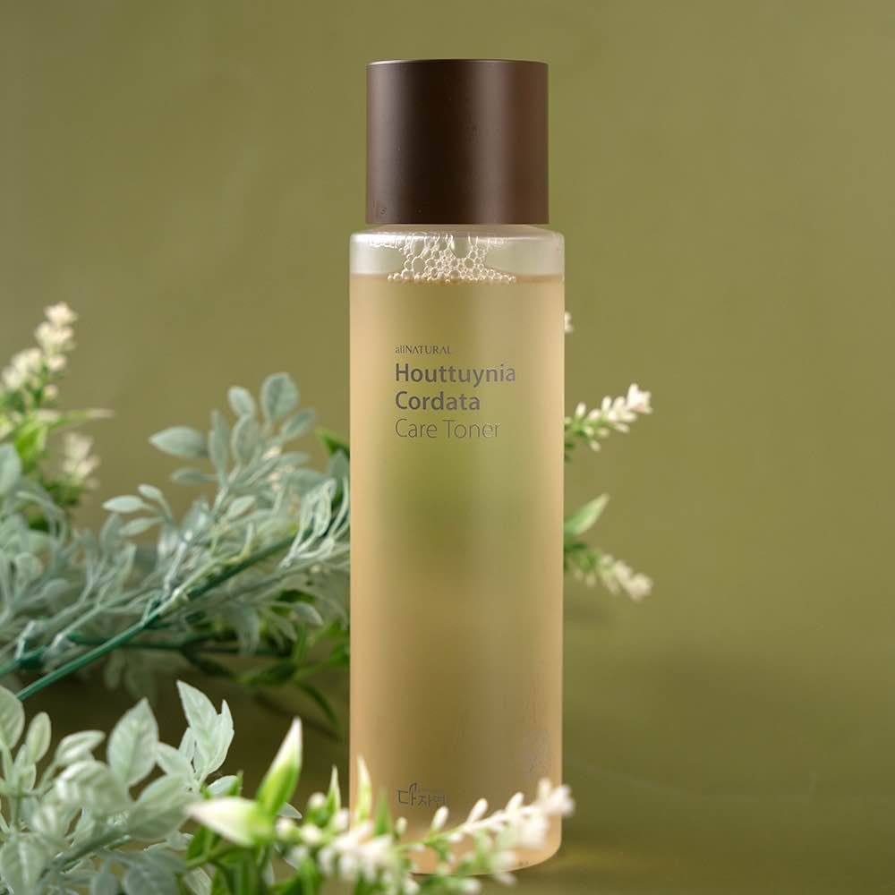 Houttuynia Cordata toner bottle with green foliage decoration against sage background.