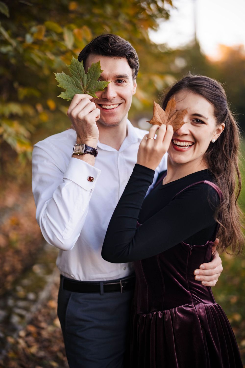 Couple laughing and sharing drinks during fall outdoor photoshoot.