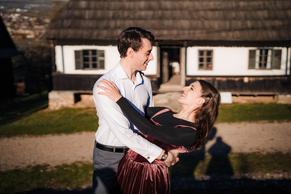 Couple embracing outside historic building with rustic wooden details.