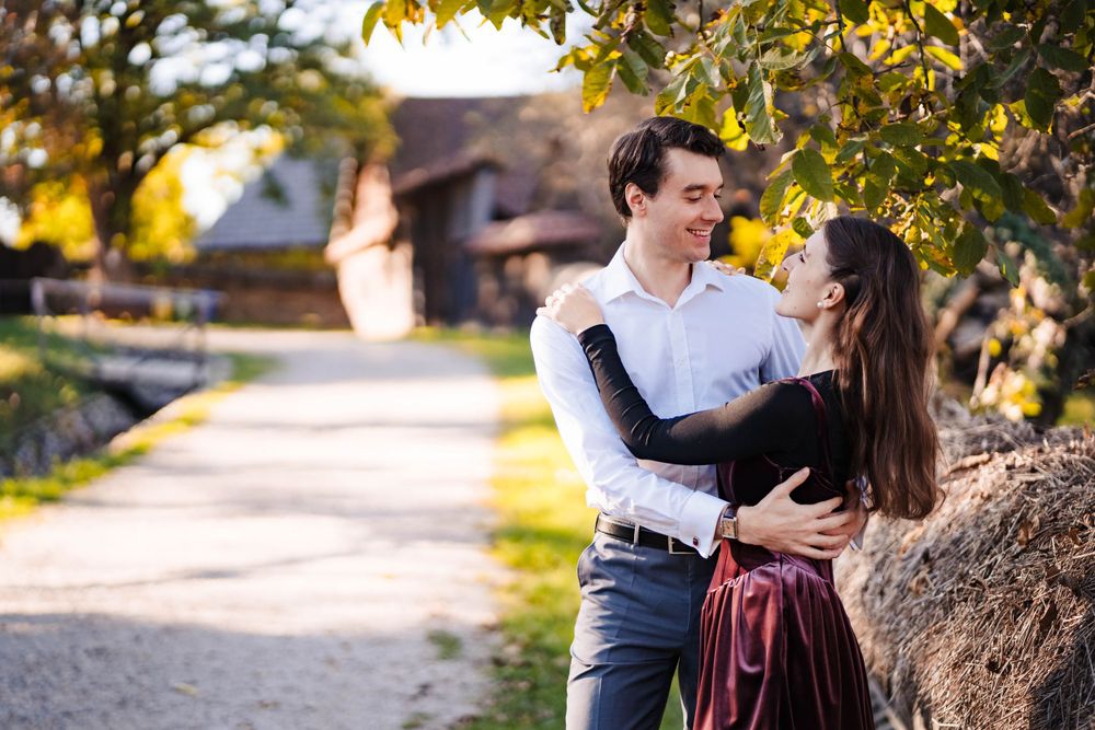 A couple embraces in a romantic autumn photoshoot under golden leaves.