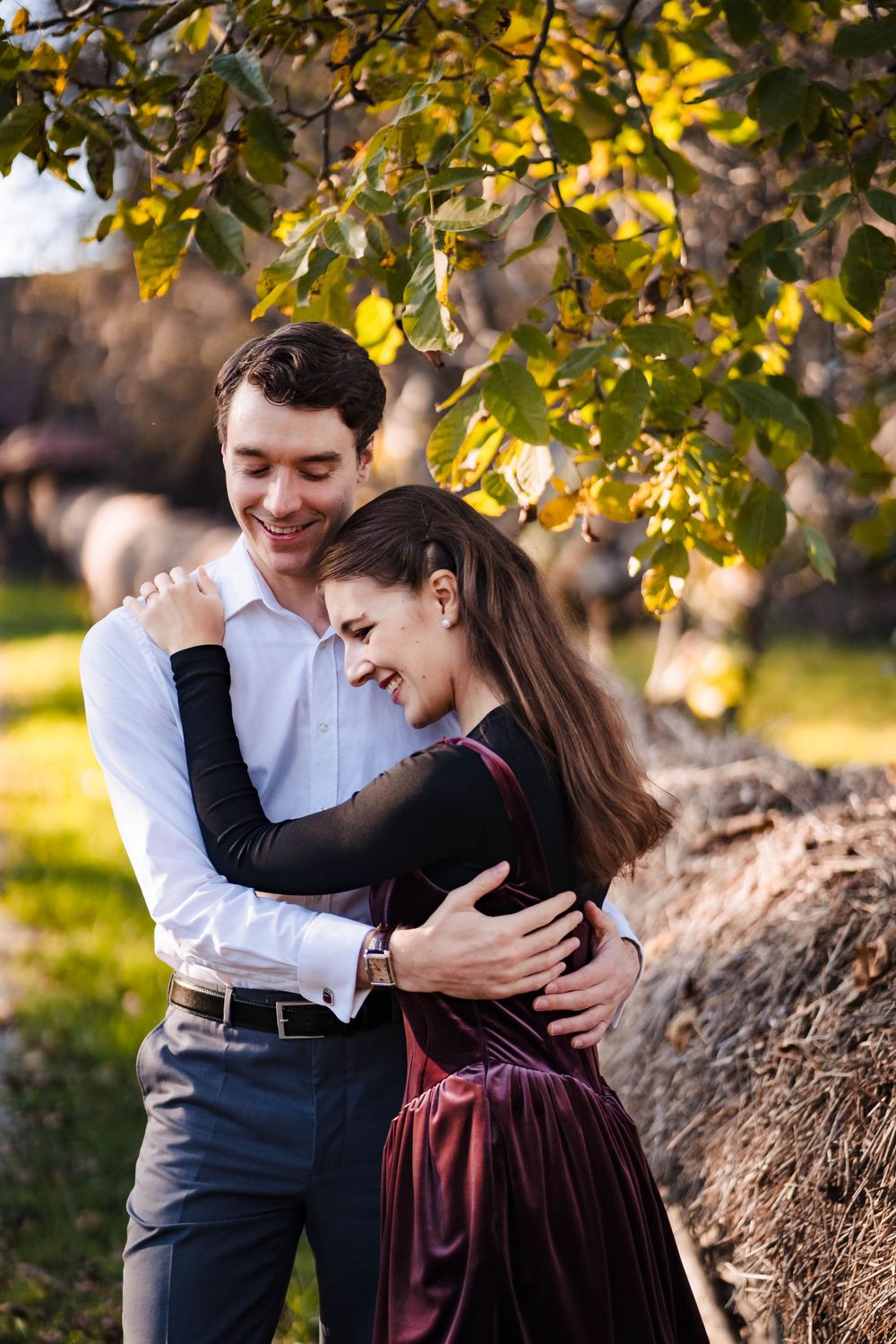 A couple shares tender moments during a fall photo session near a tree.