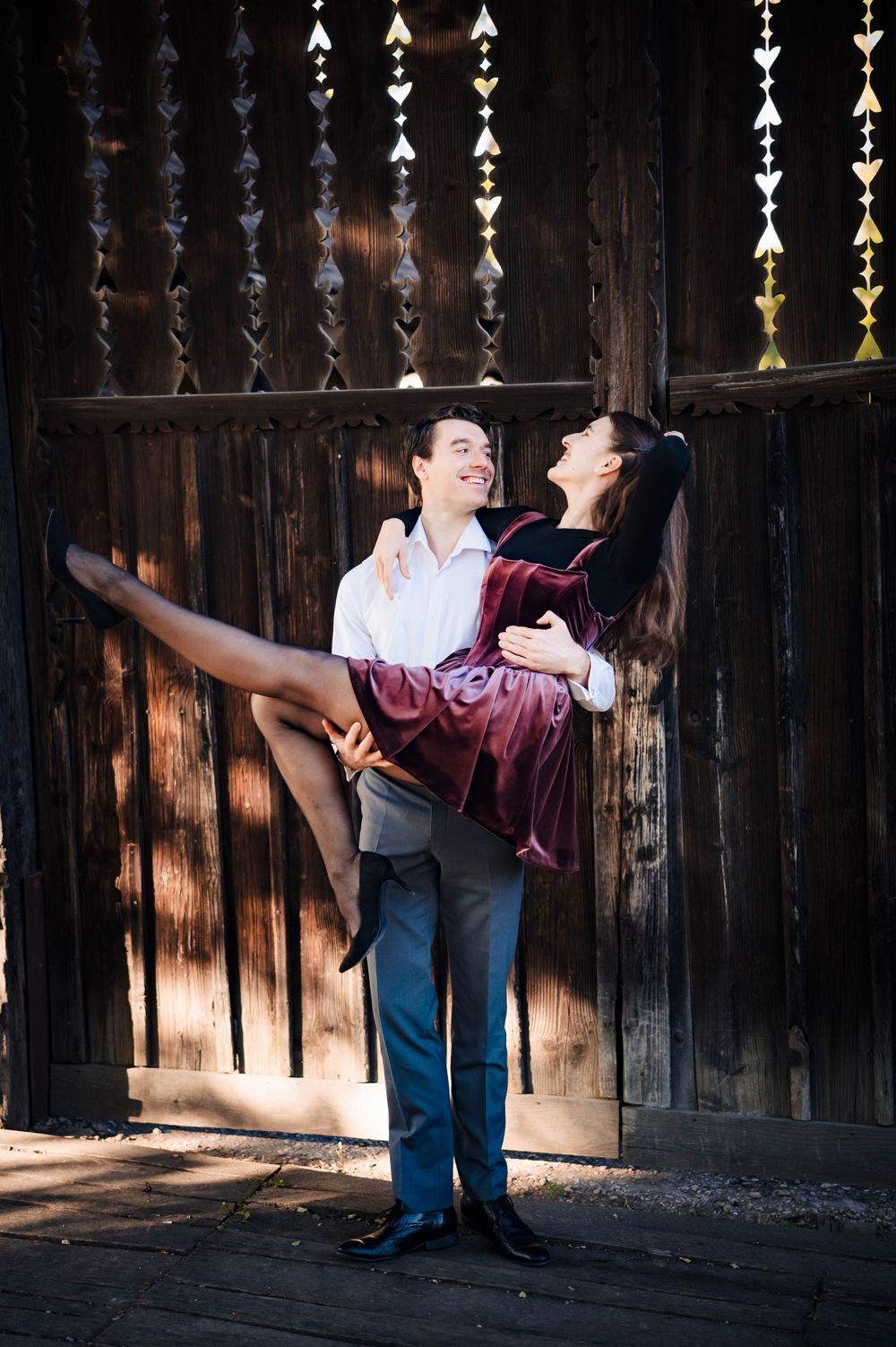 A playful dance pose against a wooden fence backdrop.