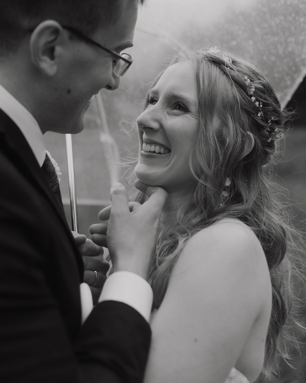 A tender candid black and white wedding portrait of a joyful bride and groom sharing an intimate moment together.