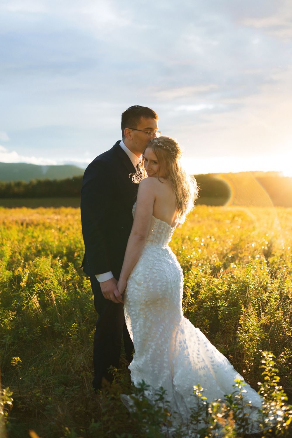 A couple shares an intimate moment in a sunlit meadow during a golden hour wedding photoshoot.