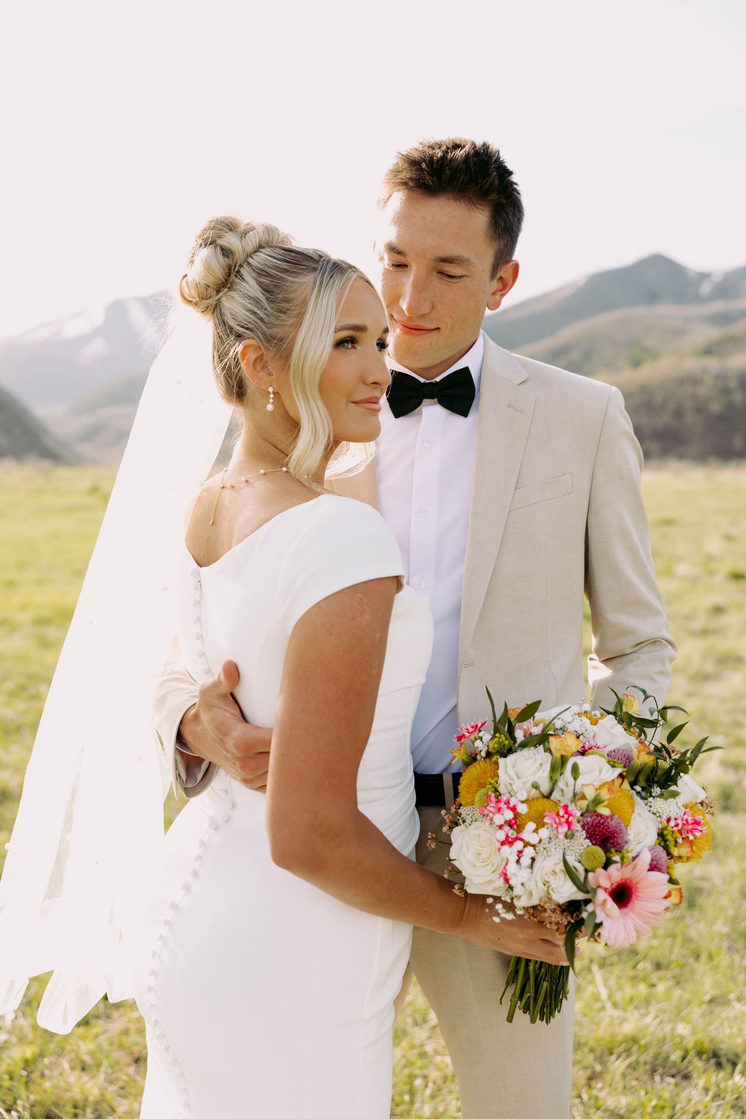 Romantic wedding portrait with elegant white bouquet against minimal backdrop.