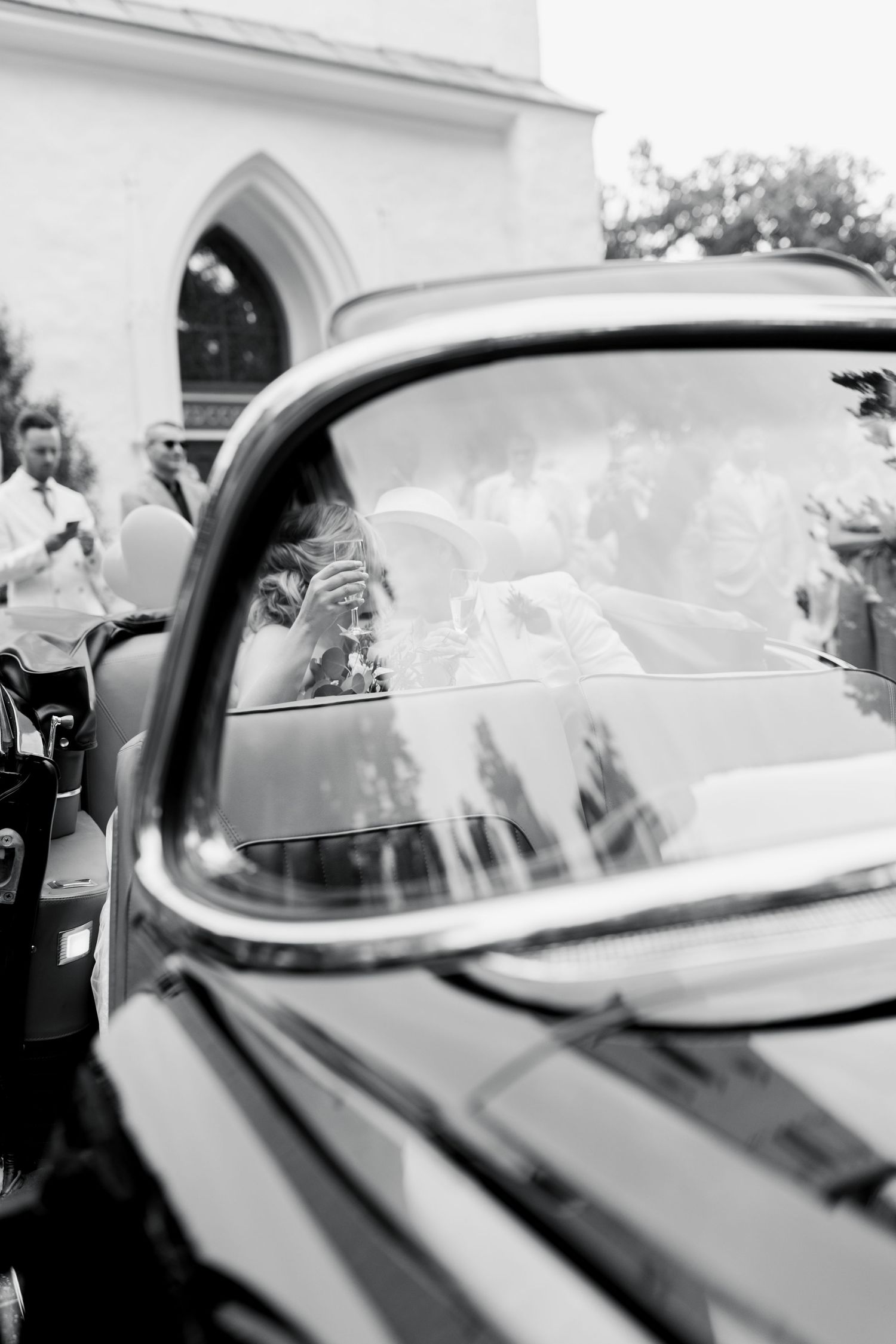 Classic car window reflection at a church wedding ceremony in black and white.