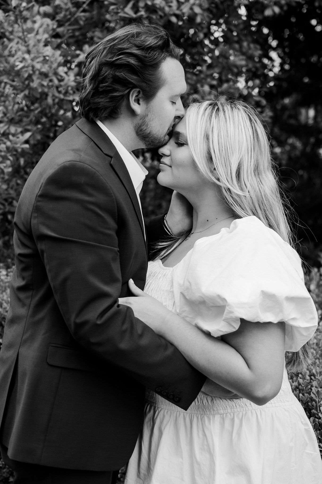 Intimate black and white portrait of romantic couple sharing tender moment outdoors.