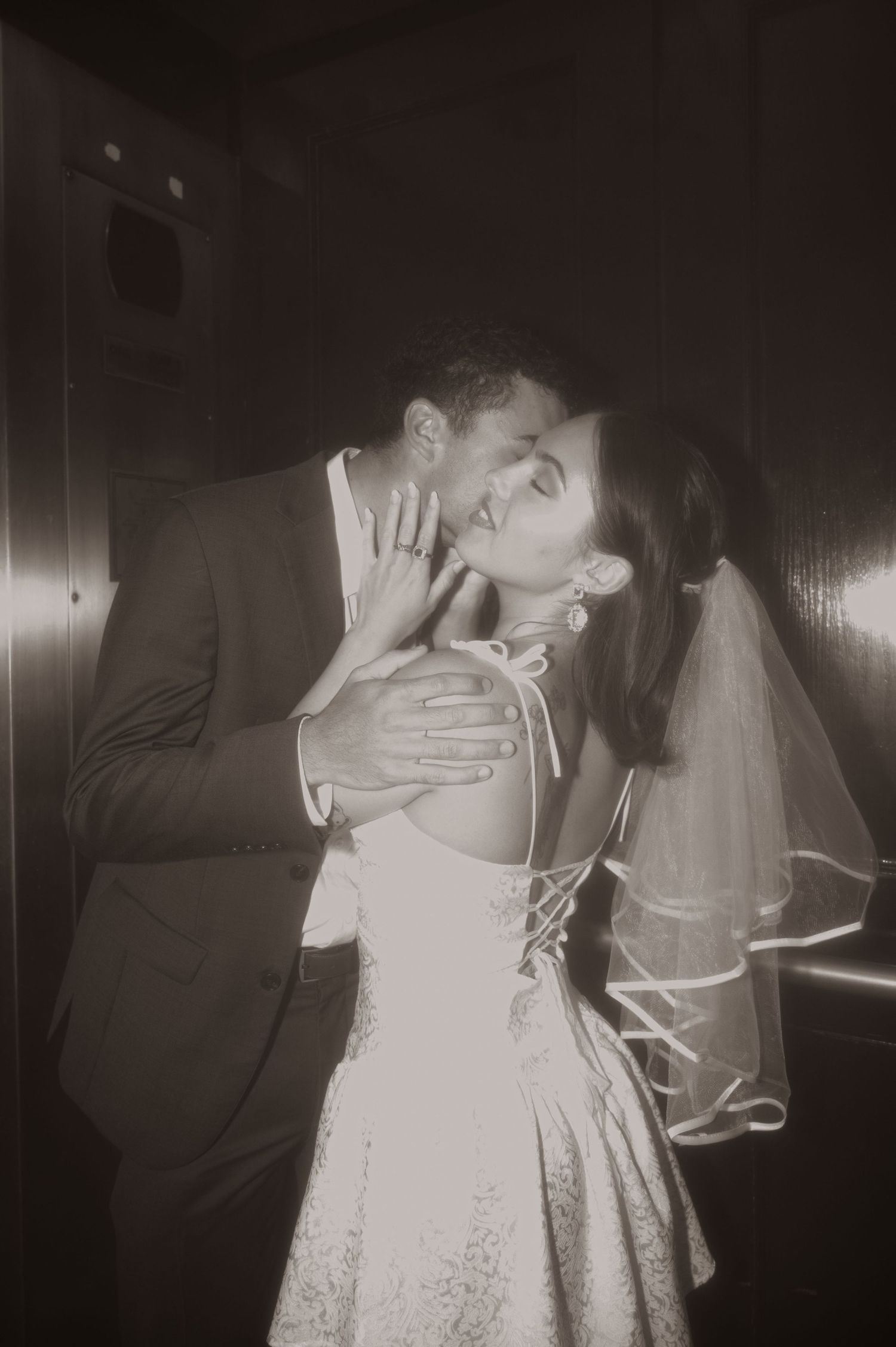 A romantic black and white photo of a couple sharing an intimate moment in wedding attire.