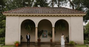 Spanish colonial style architecture features tiled roofs and arched walkways beneath shady trees.