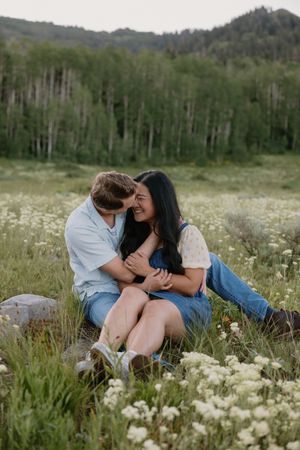 A couple shares intimate moments while lying in a wildflower meadow surrounded by aspen trees and mountains.