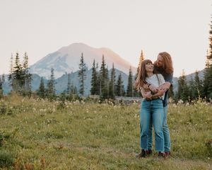 Mountain meadow with wildflowers and evergreen trees at sunset creates a scenic alpine landscape.
