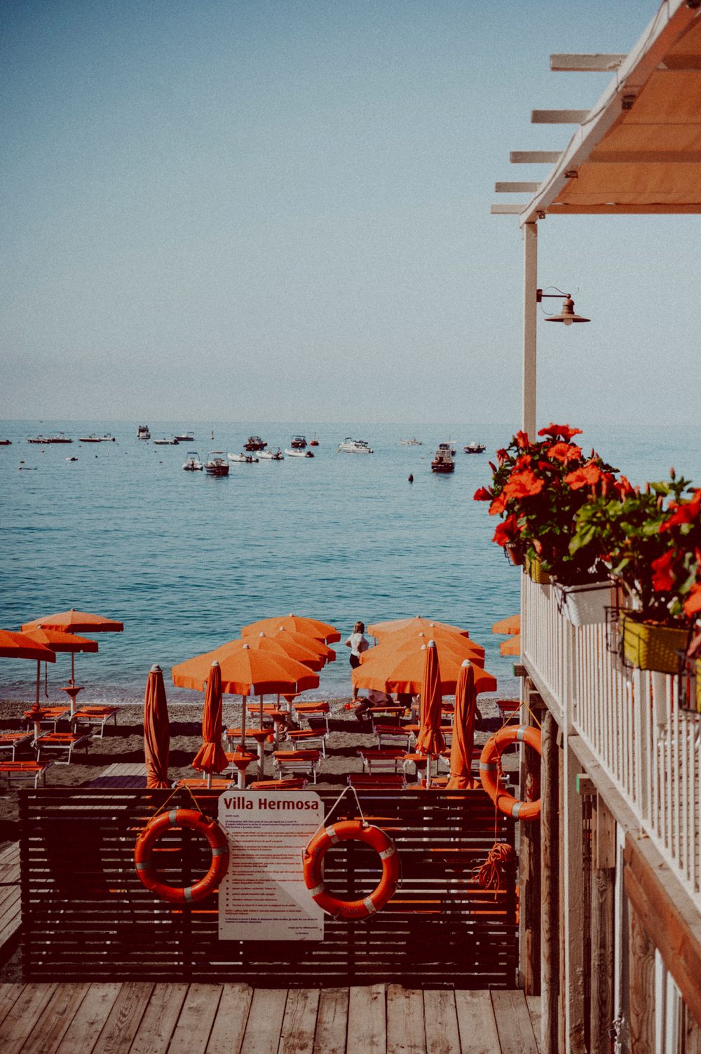 Orange beach umbrellas and white railing overlooking the calm Mediterranean sea.
