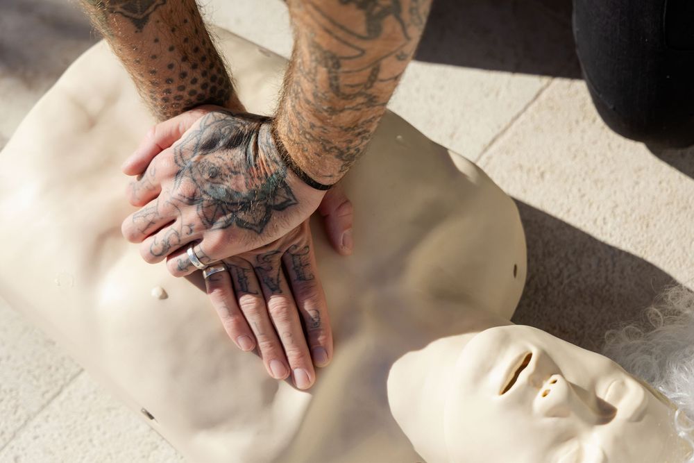 Tattooed hands preform CRP on a dummy First aid Mesh education stock photography