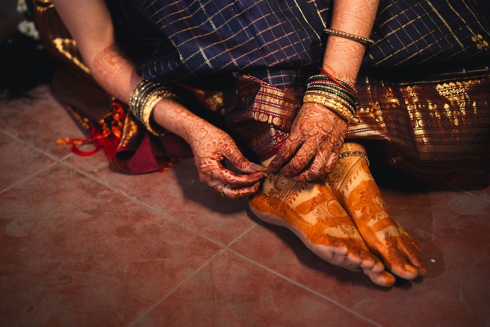 Traditional henna decorated feet and hands with bangles and jewelry during an Indian cultural celebration.