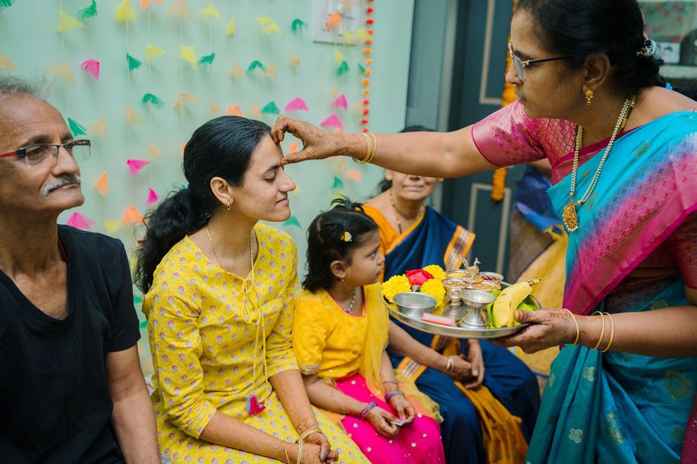 Women in colorful traditional Indian saris celebrate at a festive gathering with decorative wall confetti.