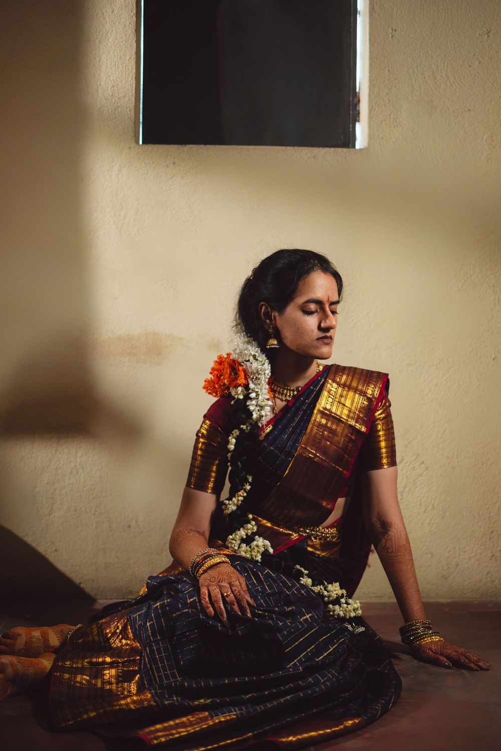 A person wearing a traditional Indian saree poses elegantly on the floor in dramatic lighting.