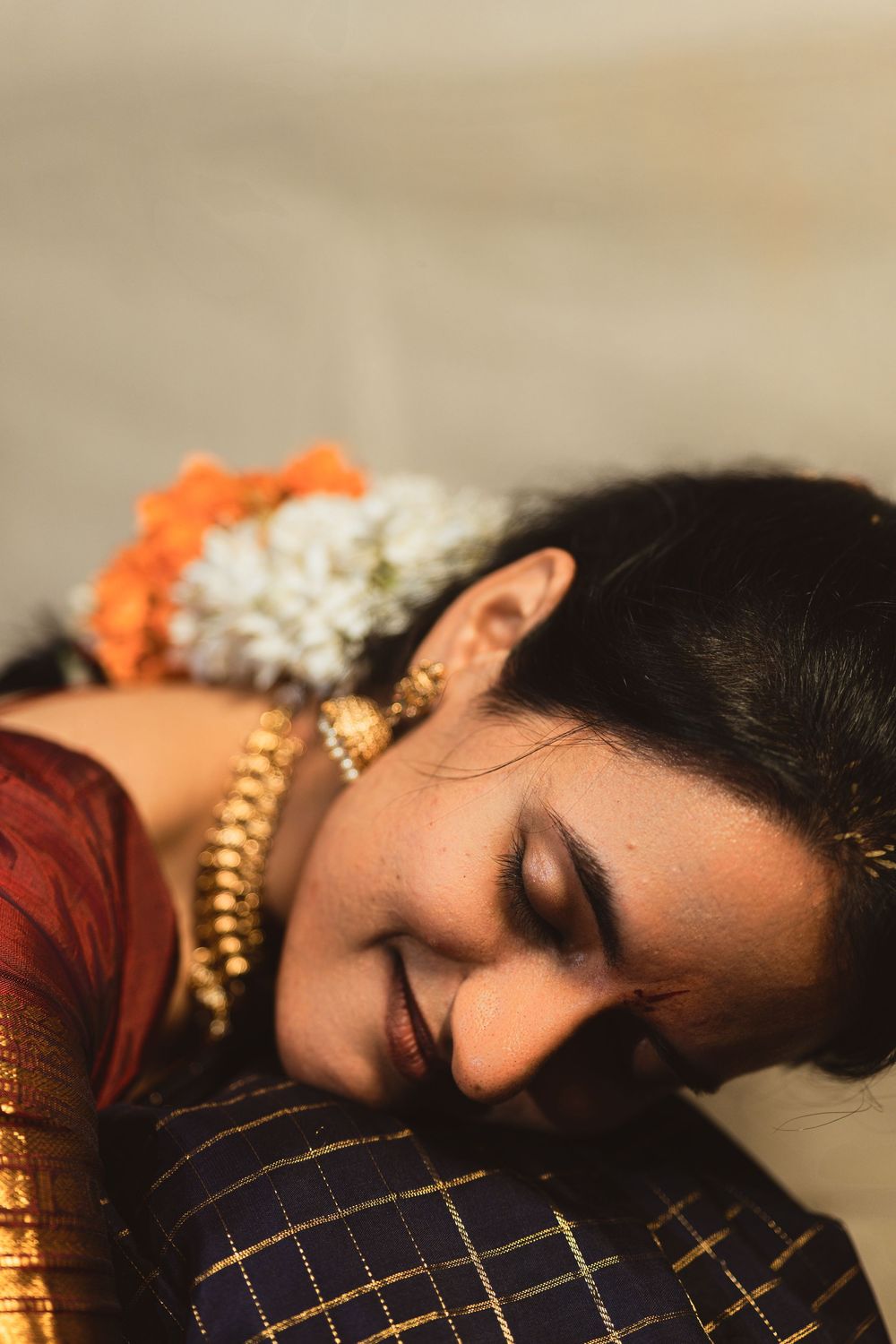 Traditional South Asian fashion with gold jewelry and flowers resting peacefully against dark fabric.
