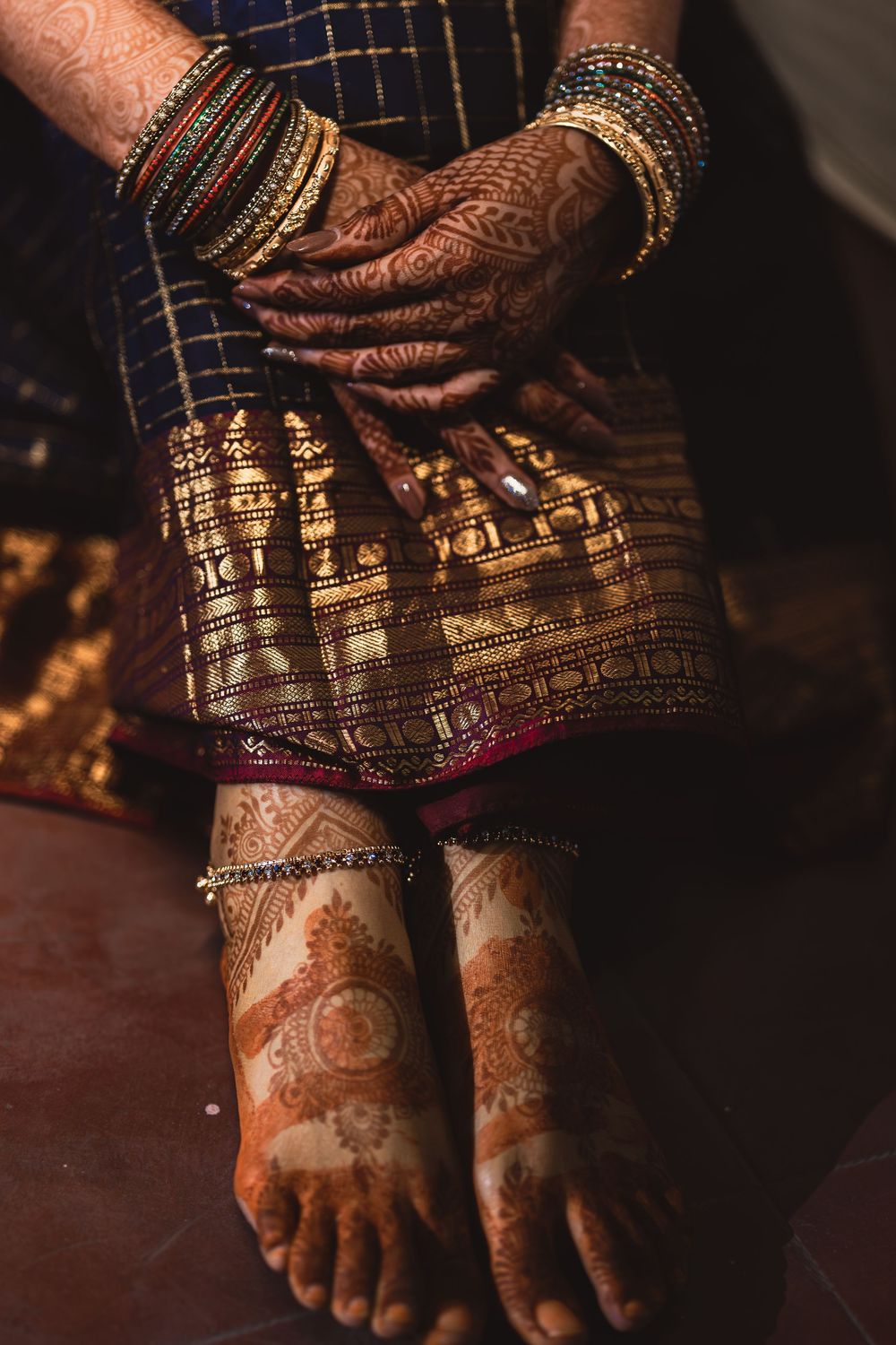 Close-up of mehndi henna designs on feet adorned with traditional Indian bridal jewelry and ornaments.