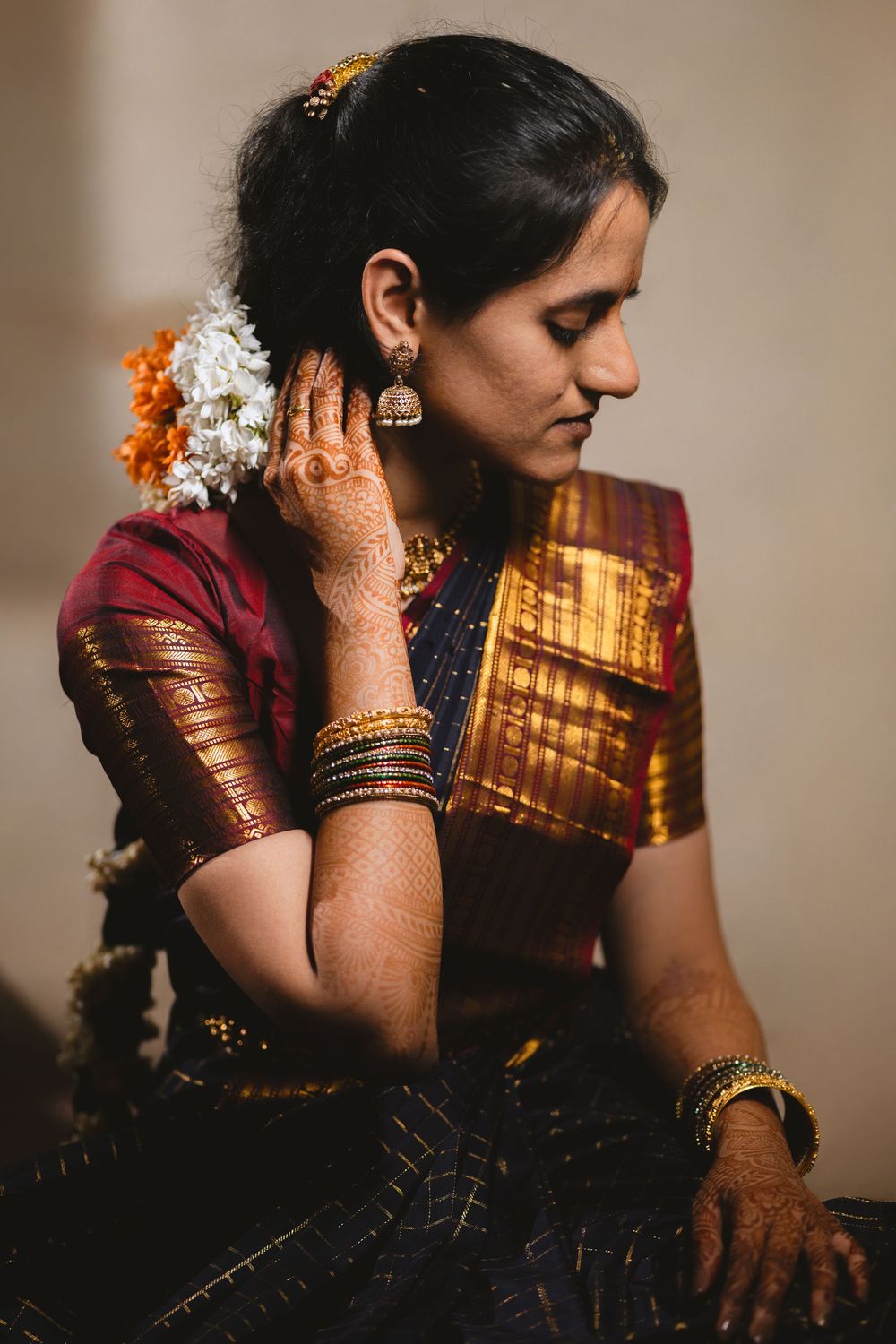 A woman in traditional Indian attire and jewelry sits thoughtfully in a dimly lit setting, creating a series of contemplative poses.