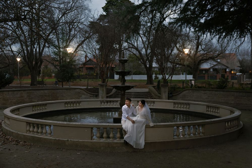A romantic evening engagement session at a curved stone balcony as dusk falls in the park.