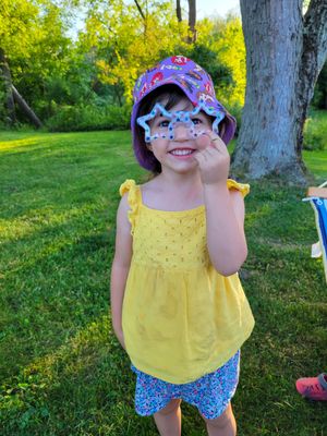 Child wearing yellow top and floral shorts playing outdoors.