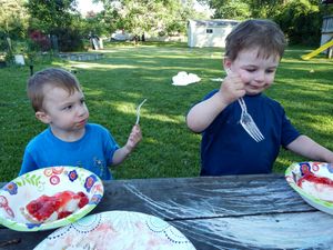 Children eating snacks at outdoor picnic table.